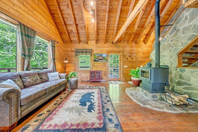 living area featuring hardwood / wood-style flooring, vaulted ceiling with beams, wood ceiling, wooden walls, and a wood stove