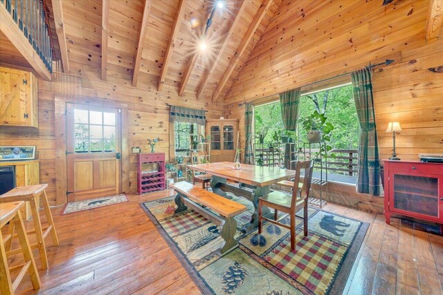 dining area with wood ceiling, hardwood / wood-style flooring, wood walls, and beamed ceiling