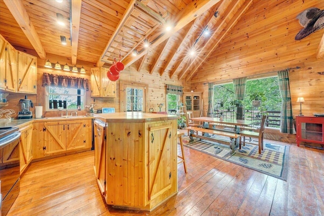 kitchen featuring light wood finished floors, a center island, beam ceiling, electric range, and wooden walls