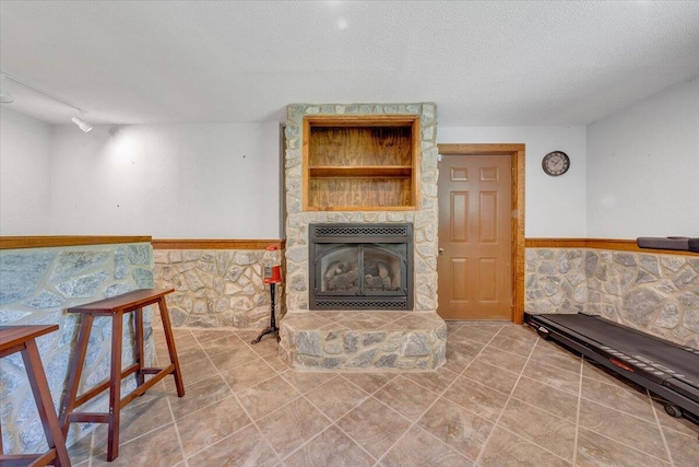 living area with tile patterned flooring, a wainscoted wall, a textured ceiling, and a fireplace