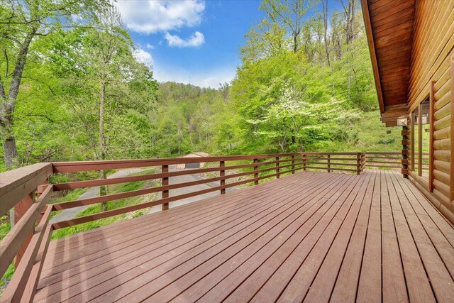 wooden terrace featuring a wooded view