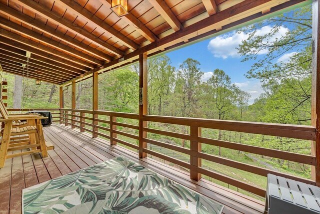 wooden terrace featuring a wooded view