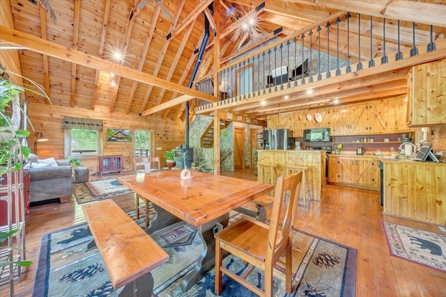 dining space with high vaulted ceiling, wood ceiling, light wood finished floors, and wooden walls