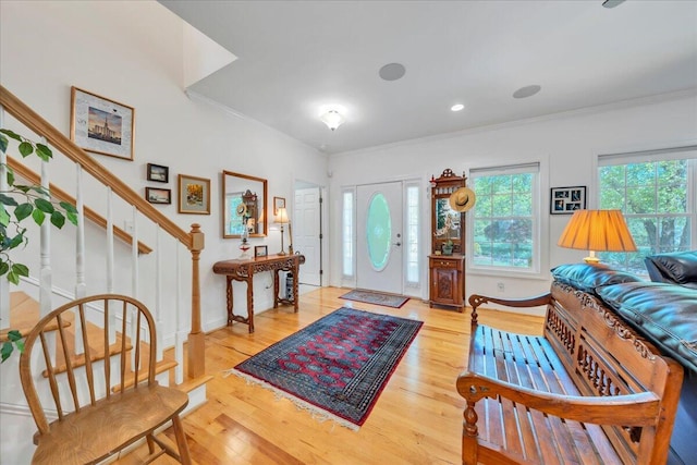 entryway with ornamental molding, baseboards, wood finished floors, and stairway