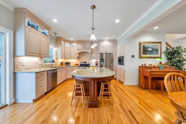 kitchen featuring a kitchen bar, light wood-style flooring, stainless steel appliances, and a sink