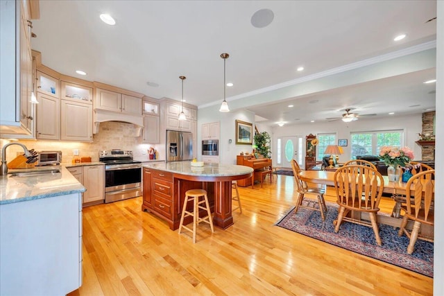 kitchen featuring ornamental molding, a sink, decorative backsplash, appliances with stainless steel finishes, and a breakfast bar area