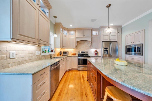 kitchen featuring light stone counters, a sink, glass insert cabinets, decorative light fixtures, and appliances with stainless steel finishes