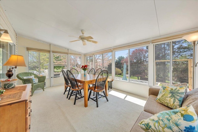 sunroom featuring outdoor dining area, vaulted ceiling, a ceiling fan, and carpet