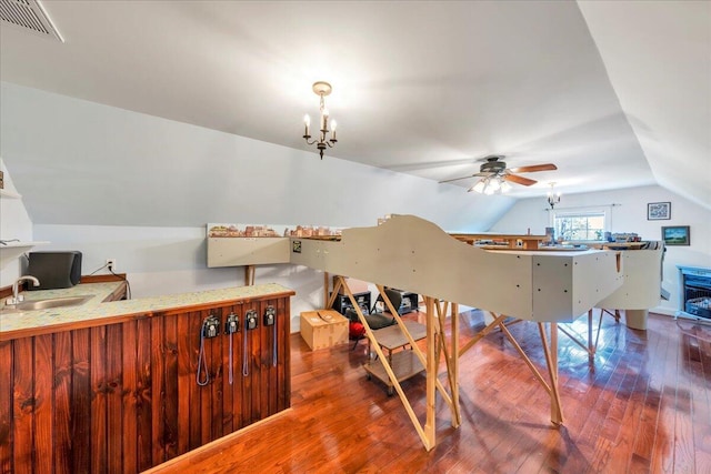 bedroom featuring a sink, vaulted ceiling, visible vents, a chandelier, and wood finished floors