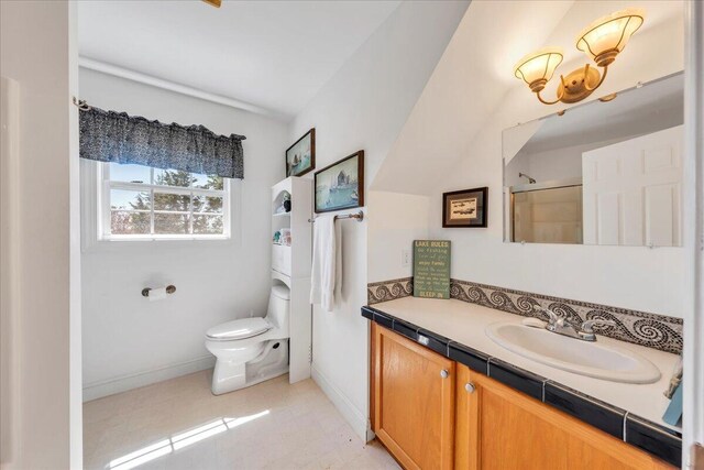 bathroom featuring vanity, toilet, baseboards, and a shower with door