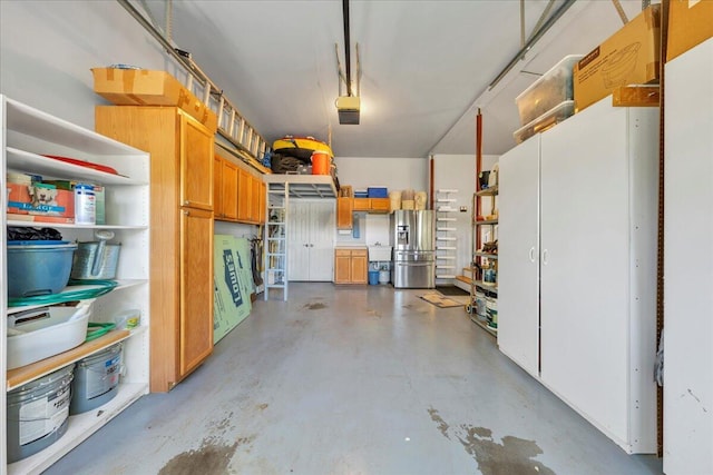 garage with stainless steel refrigerator with ice dispenser and a garage door opener