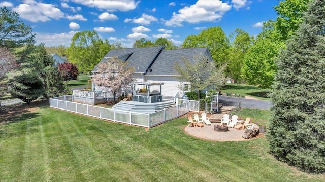 rear view of property featuring a lawn and an outdoor fire pit
