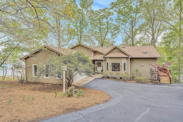 ranch-style house featuring a chimney, aphalt driveway, and a shingled roof