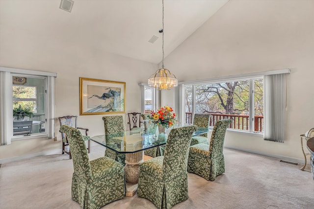 dining area featuring a chandelier, plenty of natural light, high vaulted ceiling, and light colored carpet