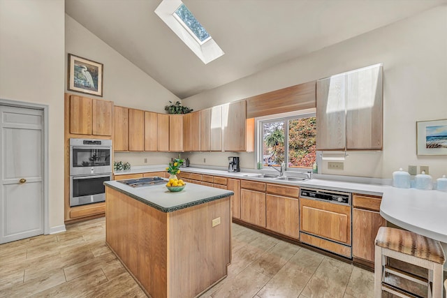 kitchen with stainless steel appliances, a sink, a kitchen island, a skylight, and high vaulted ceiling