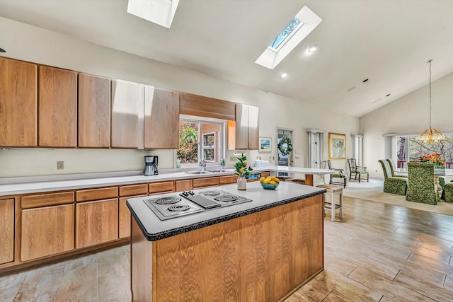 kitchen featuring a skylight, a kitchen island, stainless steel electric cooktop, and a healthy amount of sunlight