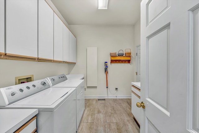 clothes washing area with washing machine and clothes dryer, cabinet space, and baseboards