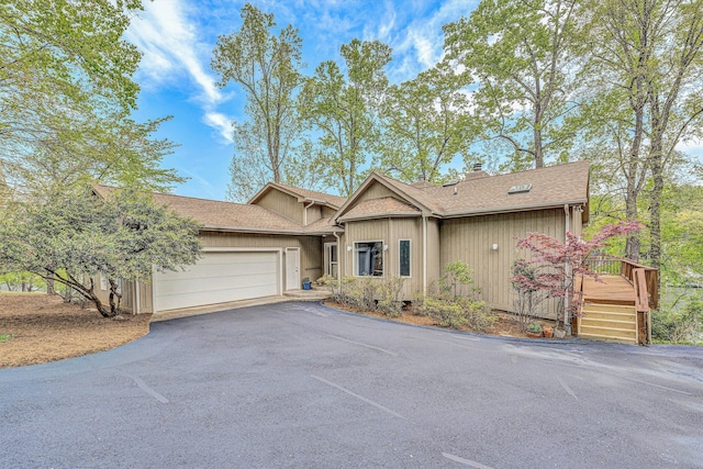 ranch-style house featuring driveway, roof with shingles, and a garage