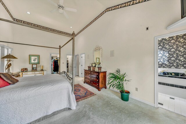 carpeted bedroom with baseboards, a closet, ensuite bath, high vaulted ceiling, and a walk in closet