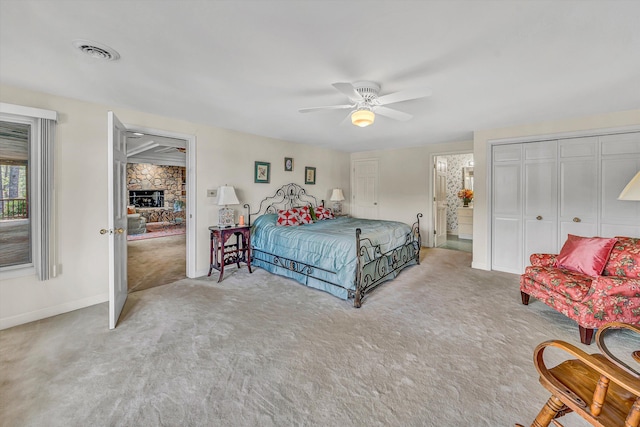 carpeted bedroom with baseboards, a ceiling fan, visible vents, and a fireplace