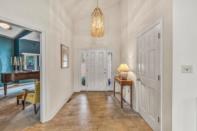 entrance foyer featuring a towering ceiling, baseboards, an inviting chandelier, and a healthy amount of sunlight