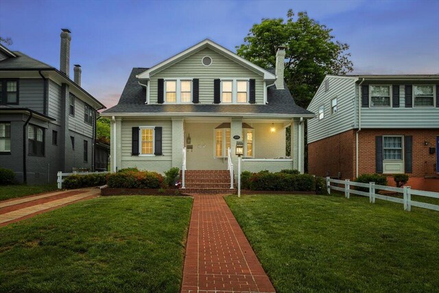 view of front of house with a chimney, a porch, a shingled roof, and brick siding