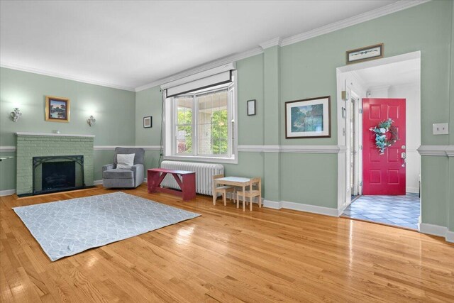 living room with radiator, ornamental molding, wood finished floors, baseboards, and a fireplace