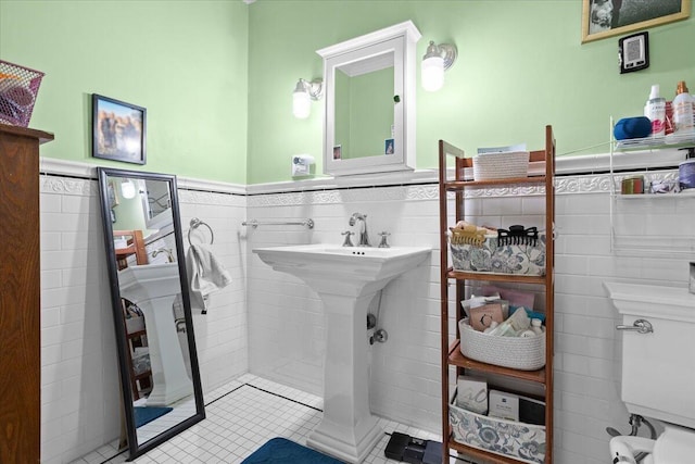 bathroom with tile walls, wainscoting, tile patterned flooring, and toilet
