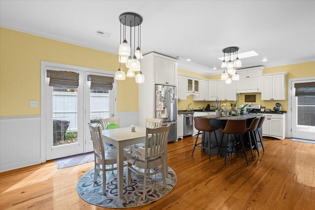 dining area with a chandelier, a wainscoted wall, light wood-style floors, ornamental molding, and recessed lighting