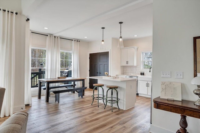 kitchen featuring white cabinets, light wood-style flooring, a kitchen breakfast bar, and a kitchen island