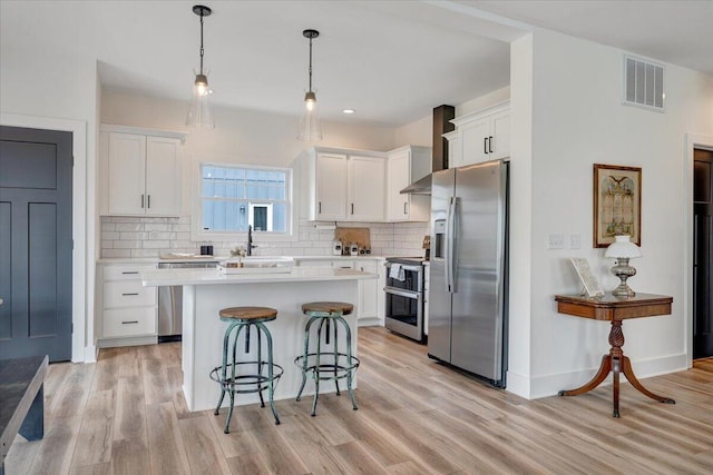 kitchen featuring visible vents, white cabinets, light wood finished floors, and stainless steel appliances