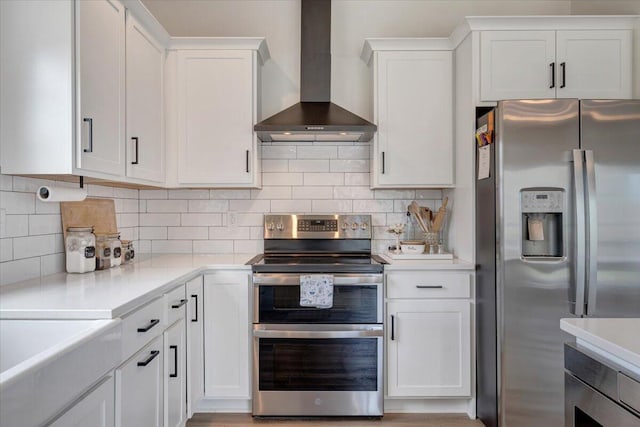 kitchen with light countertops, backsplash, white cabinets, wall chimney exhaust hood, and stainless steel appliances