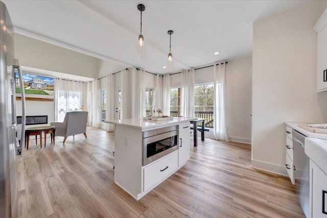 kitchen with light wood-style floors, appliances with stainless steel finishes, light countertops, and white cabinets