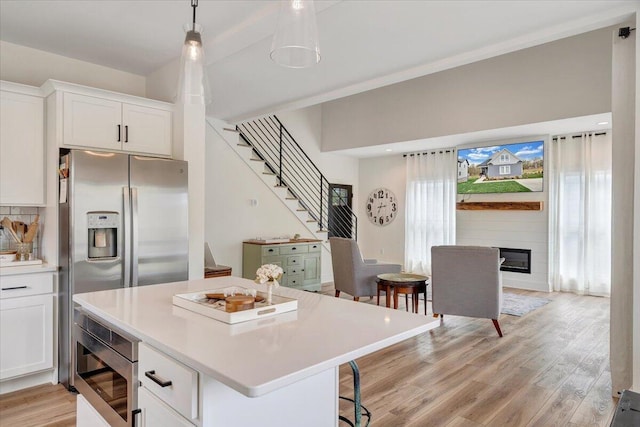 kitchen featuring light countertops, light wood-type flooring, appliances with stainless steel finishes, white cabinetry, and a kitchen island