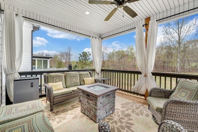 wooden terrace with a ceiling fan and an outdoor living space with a fire pit