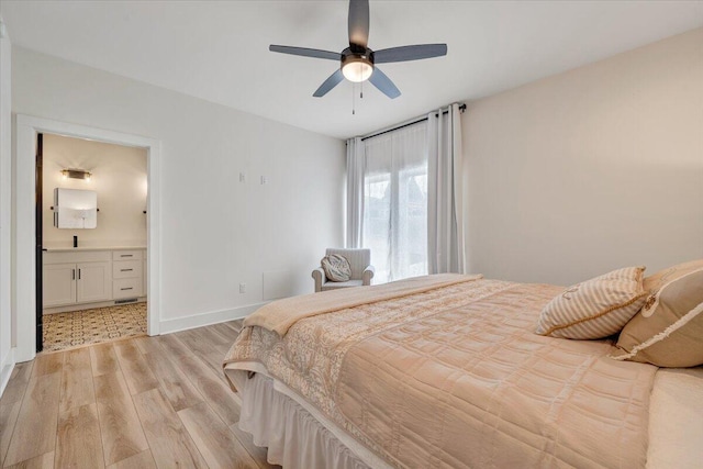 bedroom featuring baseboards, light wood-type flooring, ensuite bath, and a ceiling fan
