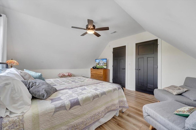bedroom featuring light wood-style floors, visible vents, a ceiling fan, and lofted ceiling