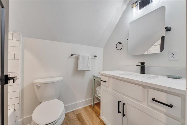 bathroom featuring baseboards, toilet, vanity, vaulted ceiling, and wood finished floors