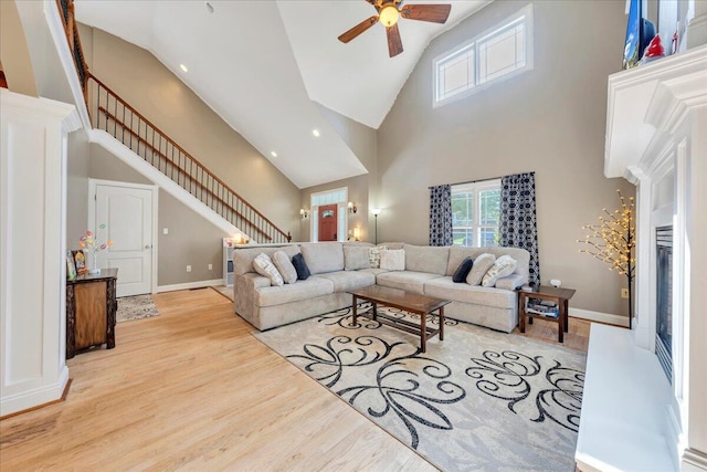 living area with high vaulted ceiling, a ceiling fan, stairs, light wood-type flooring, and recessed lighting