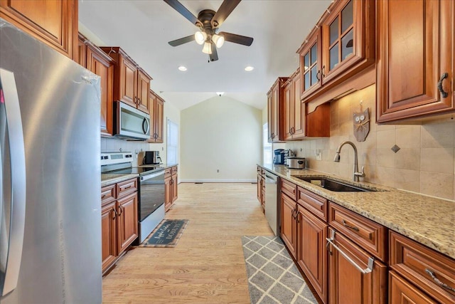 kitchen with light wood finished floors, backsplash, a ceiling fan, a sink, and appliances with stainless steel finishes
