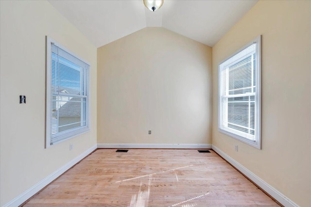 empty room featuring visible vents, baseboards, vaulted ceiling, and wood finished floors