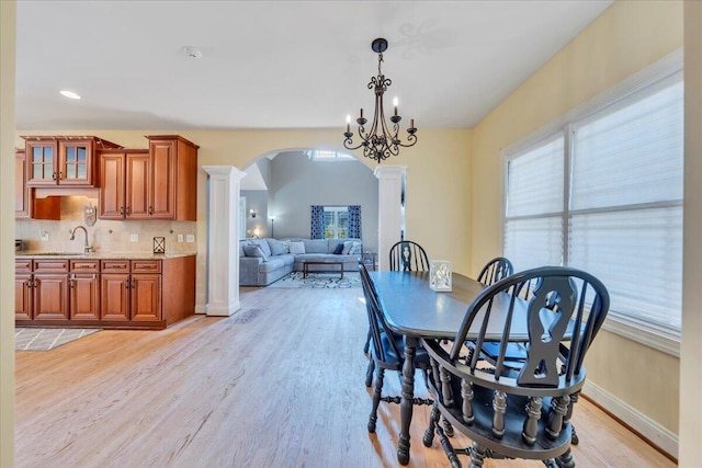 dining space with recessed lighting, arched walkways, light wood-style floors, baseboards, and decorative columns