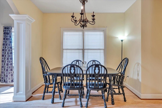 dining space with wood finished floors, ornate columns, baseboards, and an inviting chandelier