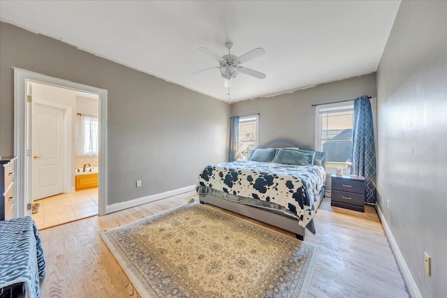 bedroom with ceiling fan, baseboards, ensuite bathroom, and light wood finished floors