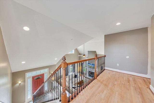 hallway with an upstairs landing, baseboards, wood finished floors, and recessed lighting