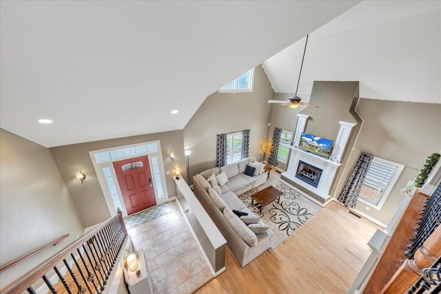 living room featuring high vaulted ceiling, wood finished floors, ceiling fan, a fireplace, and baseboards