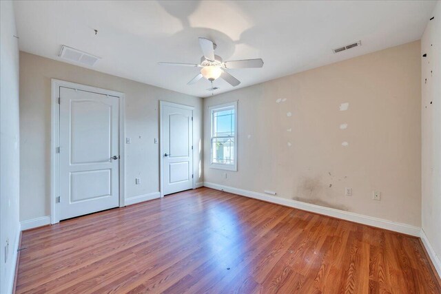 unfurnished bedroom with wood finished floors, visible vents, and baseboards