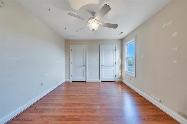 unfurnished bedroom with light wood-style floors, visible vents, baseboards, and multiple closets
