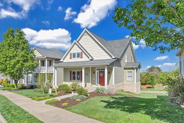 view of front facade with a shingled roof, a front lawn, and covered porch
