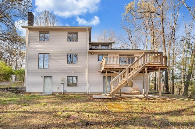 back of house featuring a chimney, a yard, a deck, and stairs